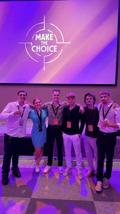 Gruppo di ragazzi davanti allo schermo di un evento, luci viola