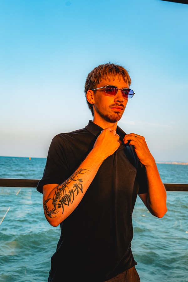 Dettaglio: mano sul colletto, tatuaggio sul braccio